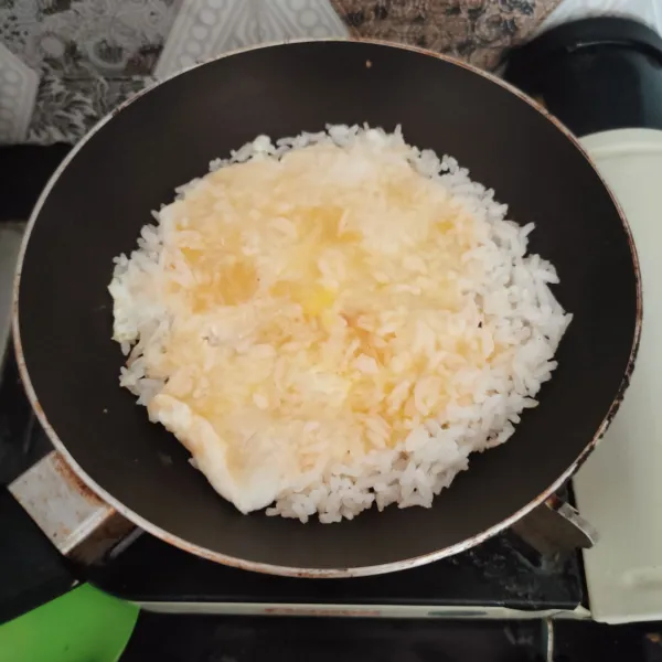 Tambahkan kocokan telur lalu beri minyak wijen sebagai penambah cita rasa. 
Masak hingga nasi berkerak dan bagian atas telur matang.