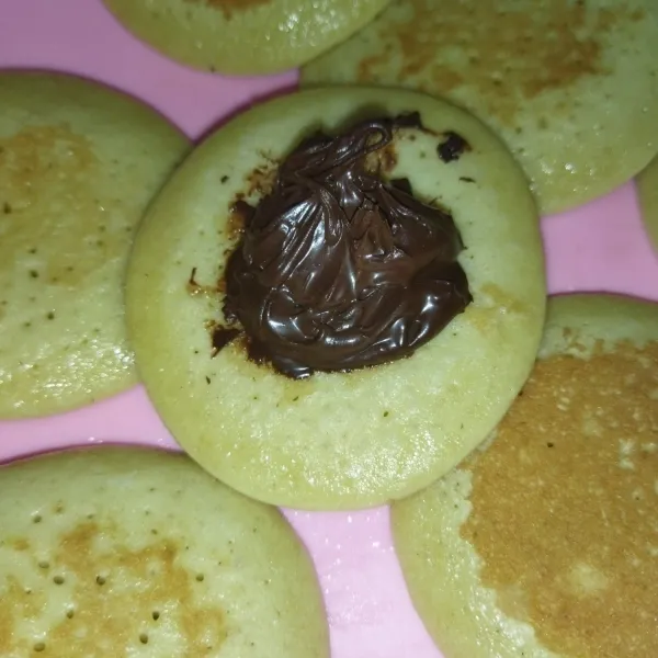 Setelah semua matang dan dingin, ambil 1 buah dorayaki dan beri selai cokelat, lalu tutup dengan 1 buah dorayaki lagi, kemudian tekan, lalu sajikan.