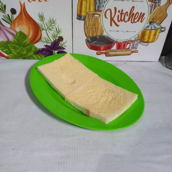 Olesi satu sisi roti tawar dengan margarin.