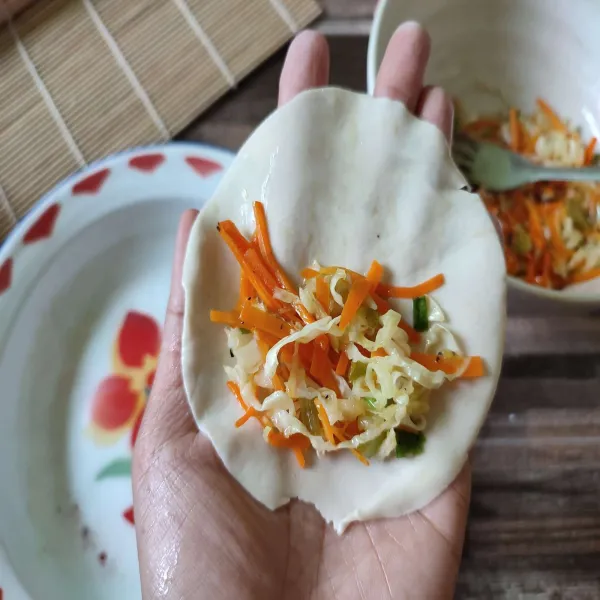 Ambil selembar kulit mandu, lalu isi dengan tumisan sayur.