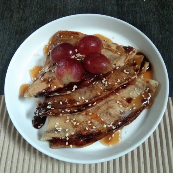 Letakkan di piring wadah, lalu hias dengan topping sesuai selera. Saya pakai biji wijen, anggur, dan saus caramel. Crepes siap disajikan.