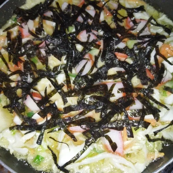 Lalu beri taburan potongan nori. Masak dengan api kecil hingga bagian bawah okonomiyaki matang.