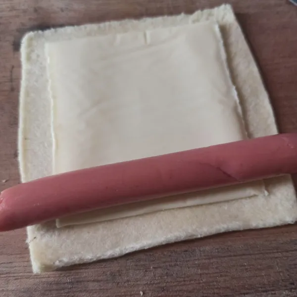 Ambil selembar roti, pipihkan. Beri keju slice dan sosis. Guling rapi, bagian ujungnya bisa diberi sedikit kocokan telur.
