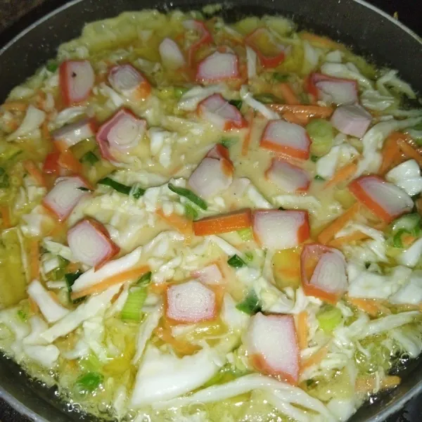 Panaskan minyak goreng secukupnya, lalu masukkan adonan okonomiyaki. Tata potongan crab stick di atasnya.