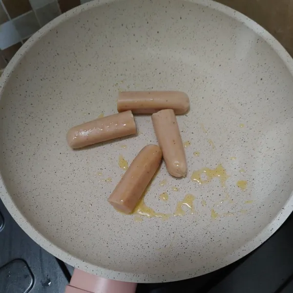 Belah sosis jadi 2 bagian, lalu goreng menggunakan margarin.