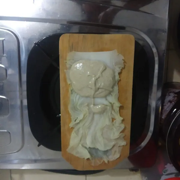 Letakkan sawi putih lalu taruh adonan siomay di atasnya dan gulung.