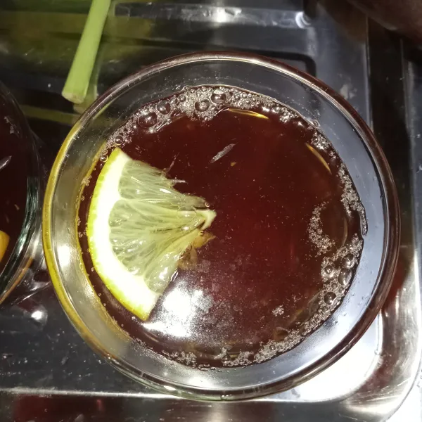 Dalam gelas masukkan potongan lemon kemudian tuang teh ke dalam gelas.
