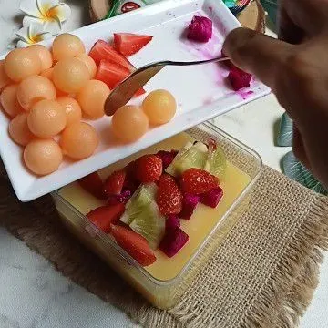 Setelah puding set, letakkan irisan buah di atas puding.