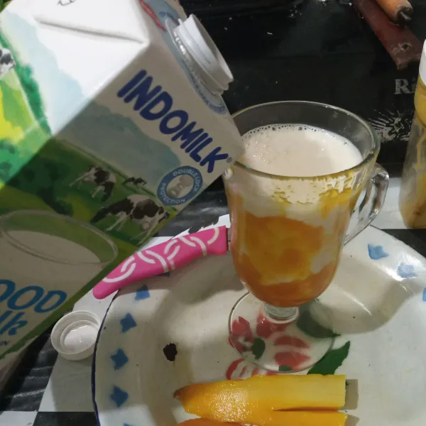 Tuang susu cair lalu beri potongan buah mangga.