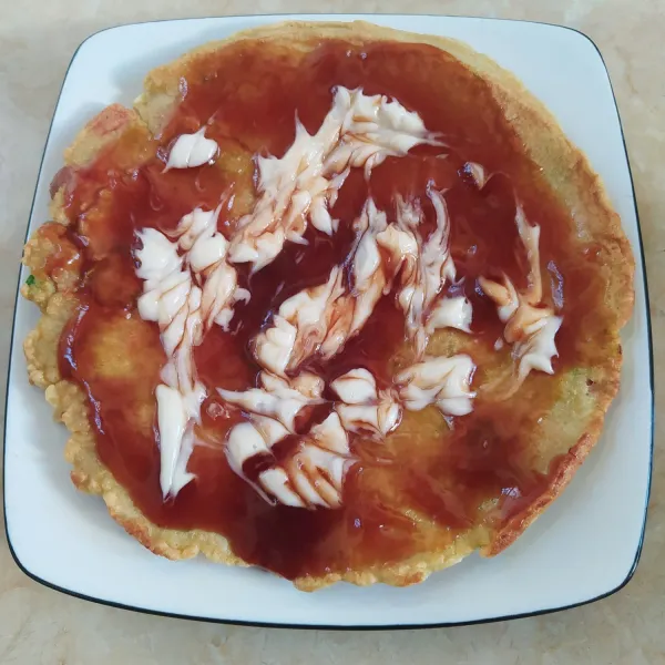 Letakkan okonomiyaki di piring, lalu beri saus dan mayonaise.