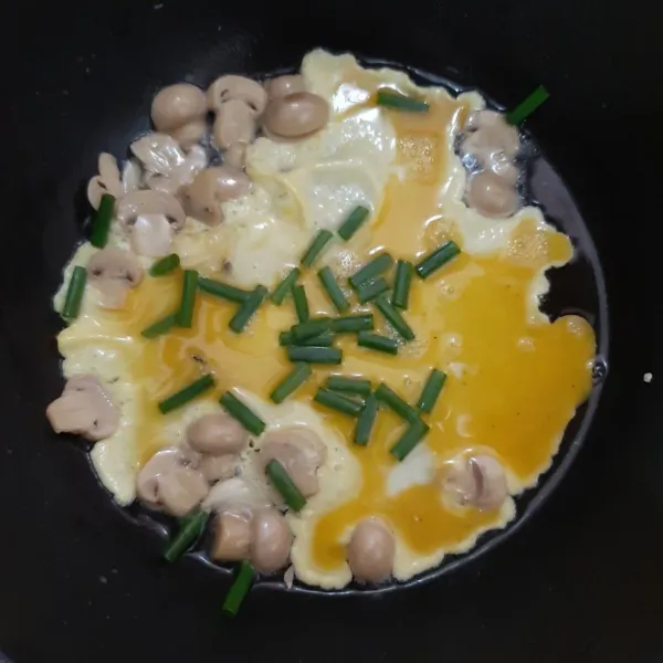 Masukkan kocokan telur dan daun bawang ke tumisan jamur.