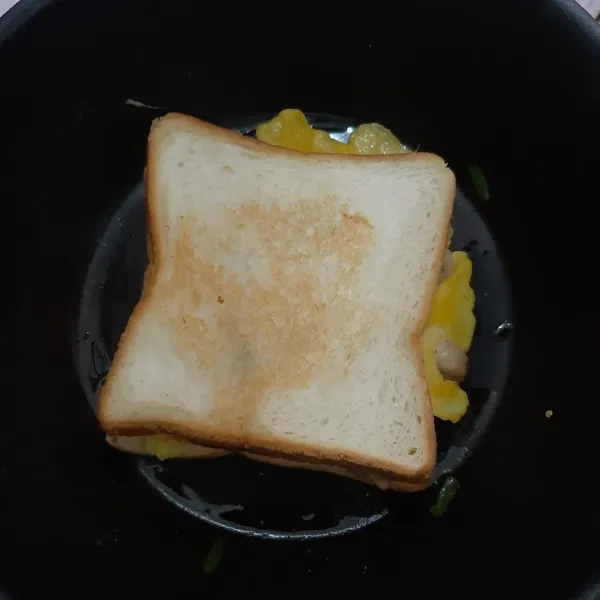 Letakkan lembaran roti ke atas telur, lalu panggang roti hingga kedua sisinya kecokelatan. Kemudian sajikan segera.