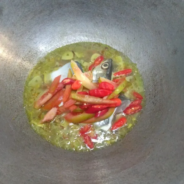 Masukkan ikan, tomat, cabai merah, dan cabai rawit, lalu aduk rata.