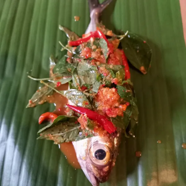 Letakkan ikan beserta bumbu di atas daun. Bungkus rapat. Sematkan lidi di kedua ujungnya.