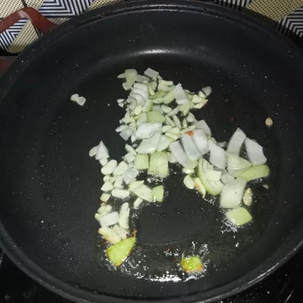 Potong-potong bawang bombay dan cincang bawang putih, kemudian tumis hingga harum.