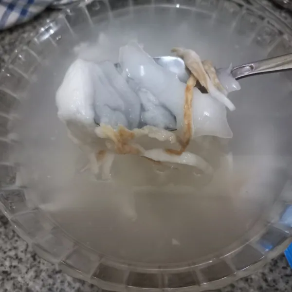 Kerok bagian daging kelapa muda, sisihkan.