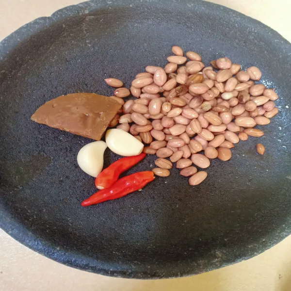 Haluskan kacang, bawang putih, cabe dan gula jawa.