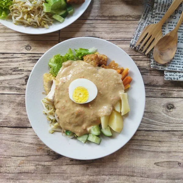 Lalu siram dengan sayuran dengan saus kacang, beri tembahan telur rebus, aduk rata, gado-gado khas Surabaya siap dinikmati.