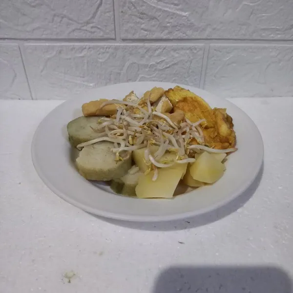 Siapkan piring saji. Masukkan irisan lontong, kentang, tahu goreng, telur, dan tauge. Kemudian siram dengan saus kacang.