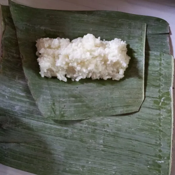 Siapkan daun pisang, letakkan nasi di bagian pinggir daun.
