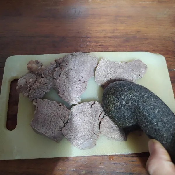 Setelah agak empuk, angkat dan tiriskan, setelah dingin iris sesuai selera.
Pukul daging dengan ulekan.
Hati-hati jangan sampai dagingnya hancur.