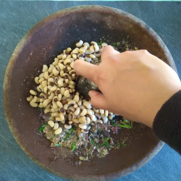 Tambahkan sebagian kacang tolo lalu ulek kasar secara bertahap. 
Lakukan sampai kacang tolo habis lalu pindahkan ke dalam wadah.