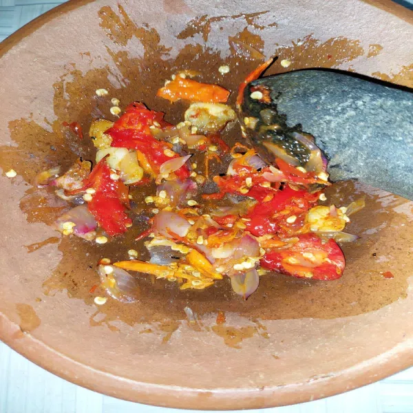 Goreng bawang putih, bawang merah, cabai keriting merah, dan cabai rawit sampai layu. Kemudian masukkan ke dalam cobek dan beri garam, lalu ulek.
