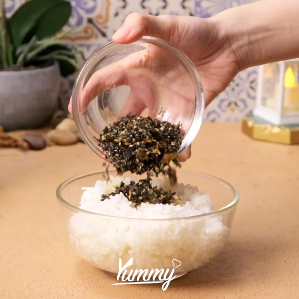 Siapkan wadah berisi nasi putih matang, kemudian tambahkan minyak wijen dan bon nori ke dalamnya. Lalu aduk hingga merata dan bentuk menggunakan tangan seperti pada gambar.