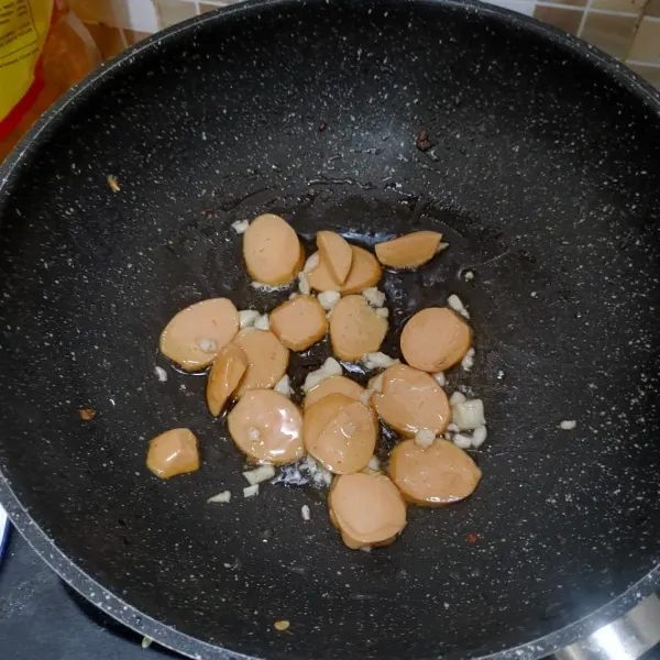Masukan irisan sosis dan aduk hingga sosis berubah warna dan matang.
