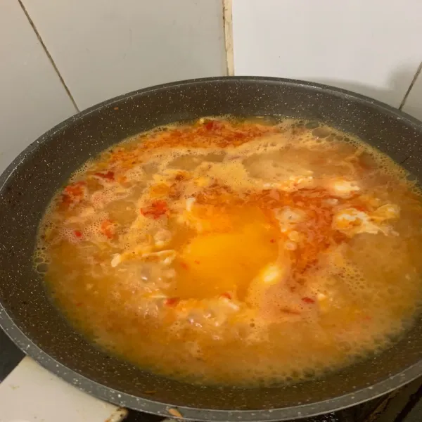 Tambahkan air kaldu, lalu ceplok telur kedalam kuahnya. Ketika air mulai mendidih tambahkan kecap asin dan kecap manis. Aduk hingga tercampur rata.