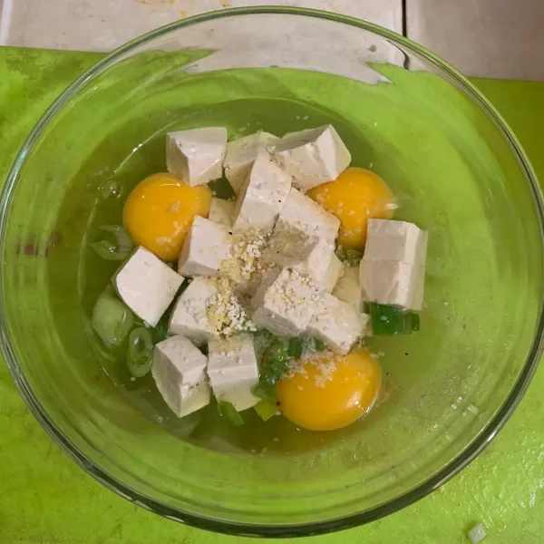 Tambahkan telur dengan daun bawang dan tahu. Berikan garam dan kaldu jamur. Kocok hingga tercampur rata.
