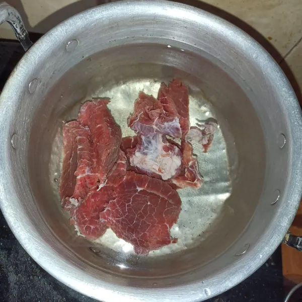 Rebus daging sampai mendidih, lalu buang air rebusan pertama dan ganti dengan air yang baru.