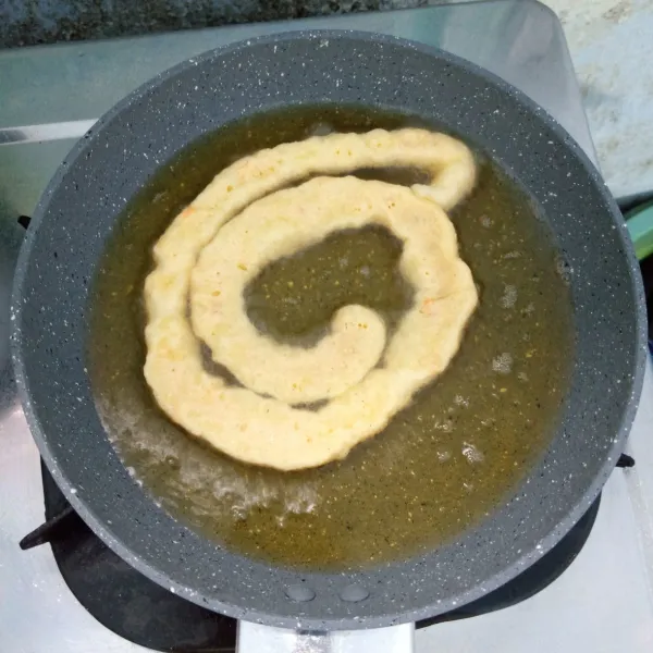 Semprotkan adonan melingkar ke dalam minyak panas. Goreng sampai matang, lalu angkat dan tiriskan. Kemudian potong-potong.