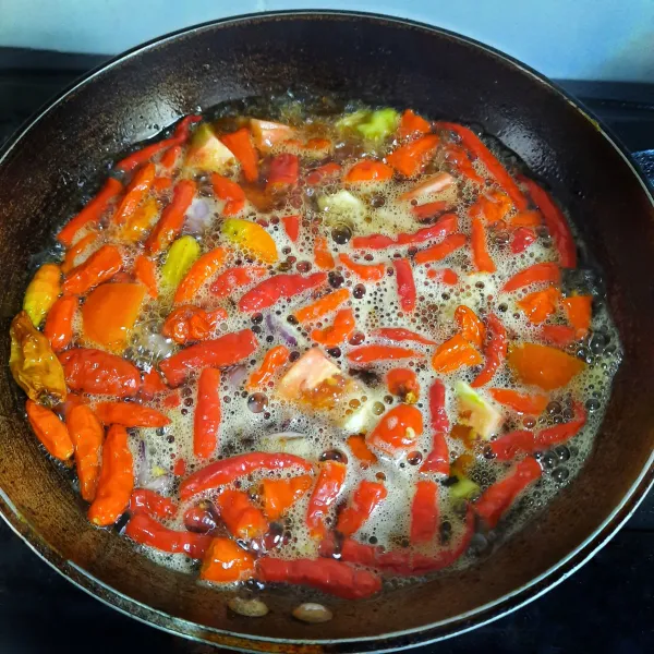 Membuat sambal: goreng cabai, tomat, terasi, bawang merah dan bawang putih hingga layu.