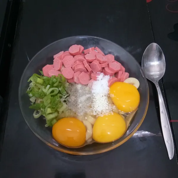 Masukkan makaroni ke dalam mangkok. Tambahkan sosis, telur, daun bawang, bawang putih bubuk, merica bubuk, kaldu jamur, dan garam. Aduk hingga tercampur rata.