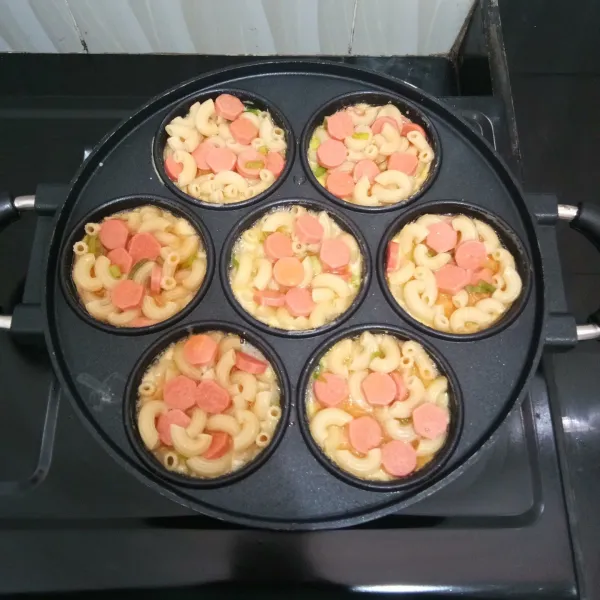 Panaskan snack maker/ cetakan kue lumpur. Beri secukupnya margarin. Lalu tuang adonan omelet hingga penuh. Masak dengan api kecil hingga bagian bawahnya matang.