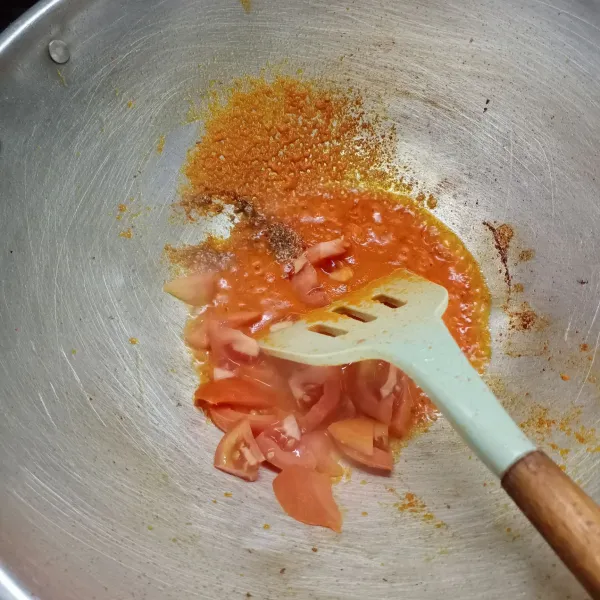 Masukkan ketumbar bubuk dan irisan tomat, aduk rata. Tumis sampai tomat agak layu.