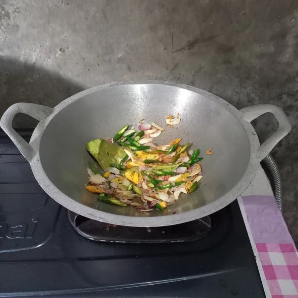 Masukkan irisan cabai, rebon, daun salam, dan lengkuas. Tumis sampai layu.