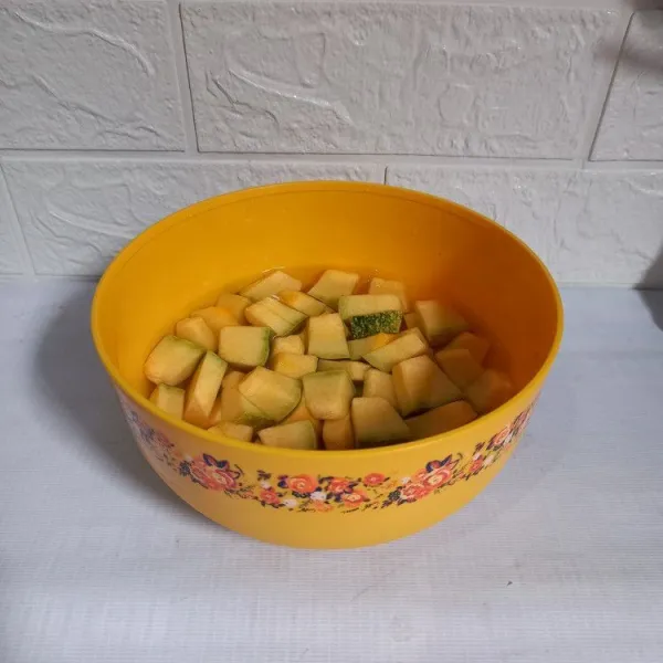 Potong-potong dan cuci labu kuning muda.