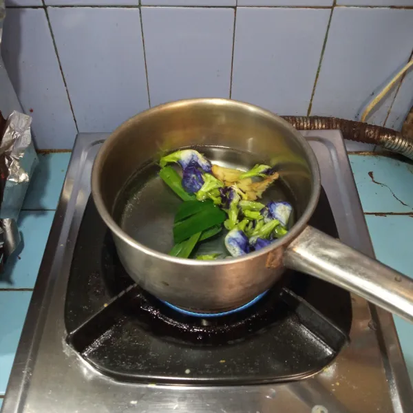 Masukkan air ke dalam panci yang sudah berisi bunga telang, jahe dan daun pandan. Rebus sampai mendidih dan air berubah warna.