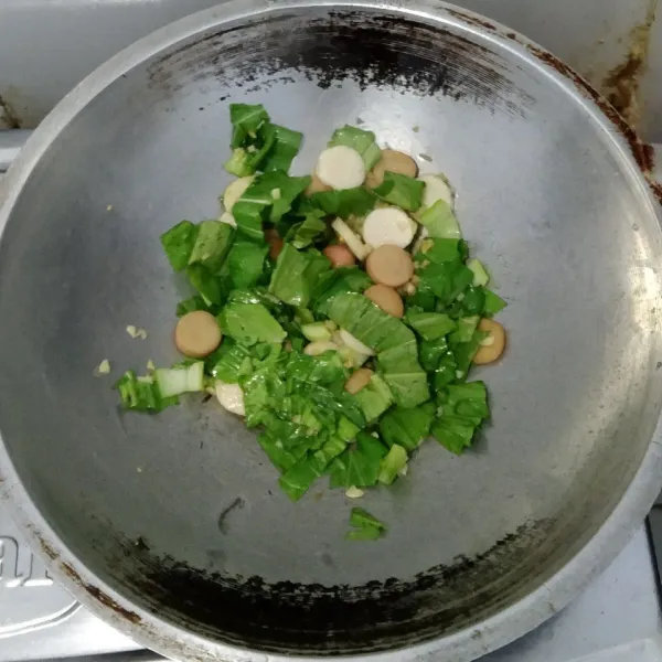 Tumis bawang putih sampai harum kemudian masukkan bakso ikan, sosis dan sawi lalu aduk kembali.