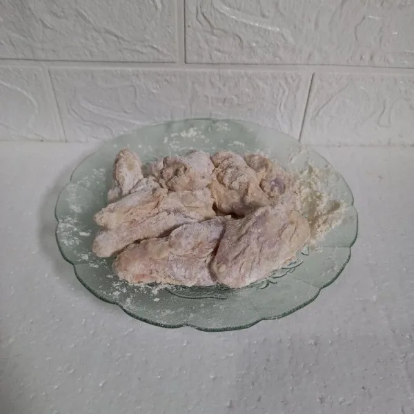 Baluri ayam dengan tepung. Jika ayam terlalu kering bisa memercikkan air supaya tepung menempel.