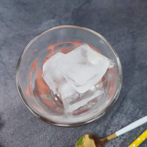 Siapkan gelas saji, masukkan es batu ke dalamnya.