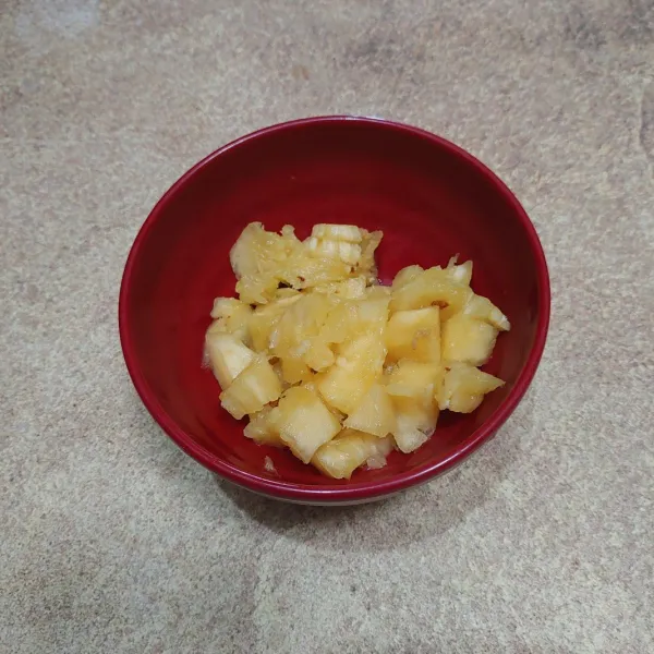 Potong kecil buah nanas yang sudah dibersihkan.