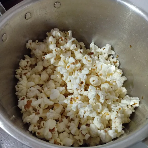 Tutup panci, masak jagung dengan api kecil sampai mengembang semua jadi popcorn, sisihkan.