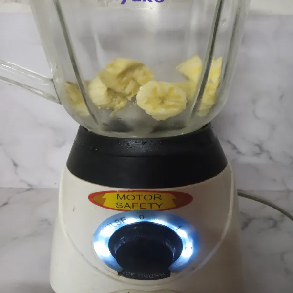 Siapkan blender, masukkan es batu secukupnya dan potongan pisang.
