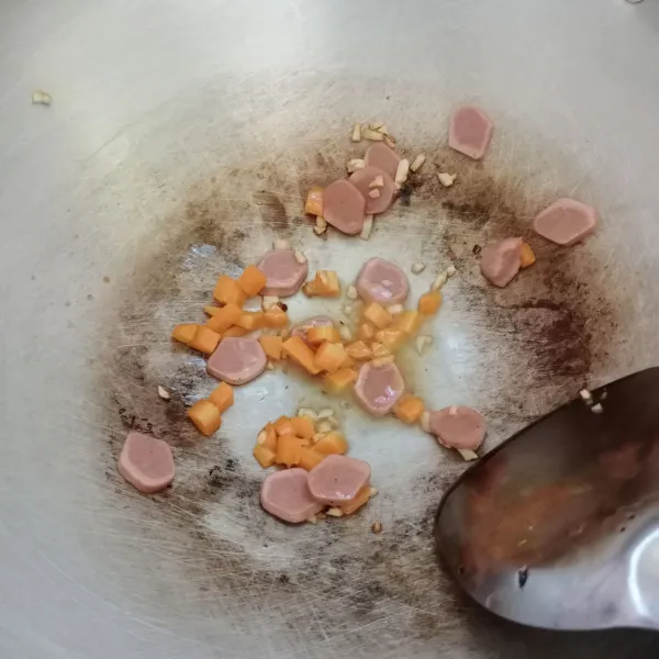 Panaskan minyak, tumis bawang putih sampai harum. Kemudian masukkan sosis dan wortel, tumis sebentar.
