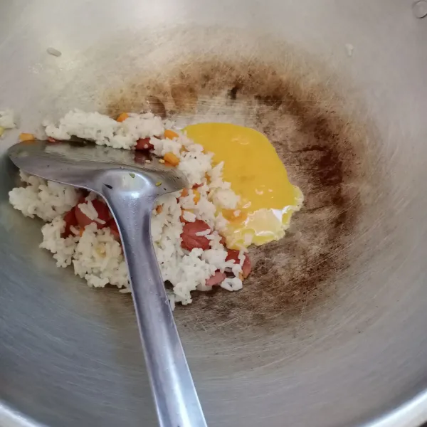 Pinggirkan nasi ke tepi wajan. Masukkan telur, buat orak-arik. Kemudian aduk rata dengan nasi.