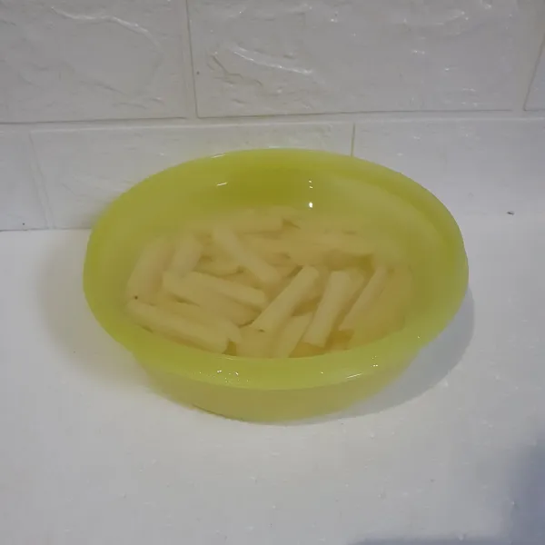 Kupas kentang dan potong memanjang. Rendam dengan air supaya tidak berubah warna.