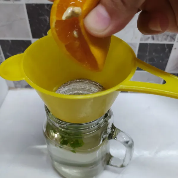 Pasang saringan di atas gelas, beri perasan jeruk calamansi 1,5 buah. 
Sisa ½ bagian dipotong-potong untuk isian.